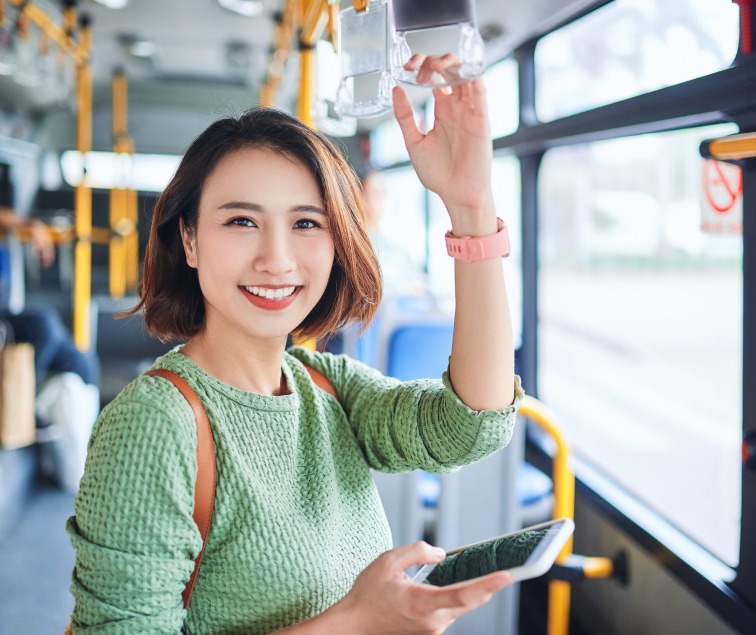 Beautiful Asian lady standing on the bus in a green sweater smiling
